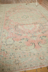 Faded blush, seafoam, and ivory tones on a distressed vintage Oushak rug with floral vinery.
