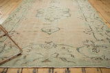 Distressed vintage Oushak carpet with faded seafoam green pattern, showing intact selvage.