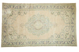 Vintage distressed Oushak carpet, ivory field with pale blue-green medallion and scrolling corners.
