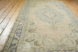 Vintage distressed Oushak rug with ivory field, scrolling spandrels, and pale blue border.