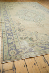 Distressed Oushak carpet border with time-softened pale blue and seafoam scrolling motifs.