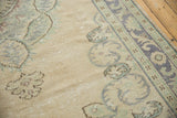 Distressed pile texture of vintage Oushak carpet with ivory ground and scrolling pale blue border.