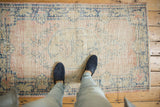 Distressed Oushak rug with wear across knot heads, dusty blush, and indigo.