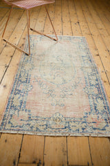 Distressed vintage Oushak rug showing worn pile, dusty blush field, and indigo blue vinery motifs.