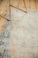 Distressed texture of a vintage Oushak rug, with faded blush and indigo blue patterns.
