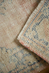 Distressed vintage Oushak rug back, showcasing hand-knotted beige, blush, and indigo foundation.