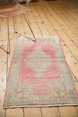 Artful distressed pile of the vintage Oushak runner, showcasing faded raspberry and seafoam motifs.