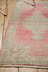 Distressed Oushak rug runner edge, showing pale raspberry and seafoam colors with even pile wear.