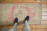 Distressed Oushak runner with faded pink, seafoam green, and ivory octagonal medallion.