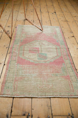 Distressed vintage Oushak rug showing soft dusty rose and seafoam green geometric pattern.
