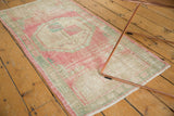 Distressed pink and seafoam green Oushak runner corner, showing even wear and fringed edge.