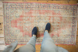 Distressed vintage Oushak runner with faded blush and ivory, showing worn texture.