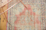 Distressed Oushak runner's worn knot heads with faded blush, ivory, and blue patterns.