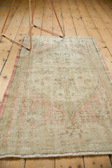 Distressed Oushak runner with faded seafoam green, dusty blush, and visible wear to knot heads.