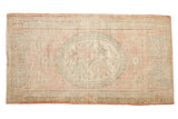 Distressed vintage Oushak rug with a faded pink, ivory, and seafoam green medallion.