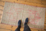 Vintage distressed Oushak rug corner with worn pink, seafoam green pile and intact selvage.