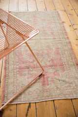Distressed Oushak runner detail showing worn pink and pale green pile with exposed foundation.