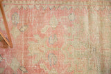 Distressed Oushak rug pile detail, featuring wear, exposed knot heads, and blush, pale green tones.