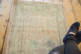 Distressed Oushak runner corner, revealing seafoam green and ivory pile with even wear.