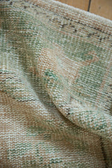 Distressed hand-knotted Oushak rug pile, showing even wear, faint foundation, and muted seafoam.