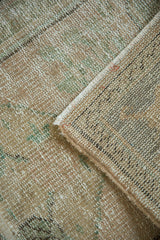 Distressed Oushak rug pile texture showing wear, faint foundation, and soft green tones.