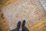 Faded dusty rose, sand, and brown palette on a distressed vintage Oushak rug with primitive medallion.