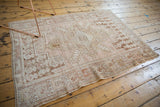Distressed vintage Oushak rug corner, faded dusty rose, sand, coffee brown patterns, visible knot wear.