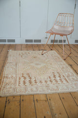 Distressed Oushak rug corner, time-softened beige and ivory with geometric brown border, low pile.