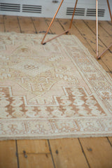 Distressed vintage Oushak rug displaying faded dusty rose and coffee brown geometric patterns.