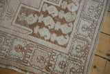 Vintage distressed Oushak rug showing muted geometric patterns and soft texture along its side.