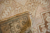 Distressed Oushak rug corner revealing faded rose-sand pile and woven coffee brown patterned reverse.