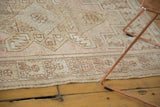 Distressed vintage Oushak rug corner, faded rose and sand geometric pattern, intact selvage.