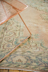 Distressed vintage Oushak rug section, revealing worn pile, subtle rose and seafoam green patterns.