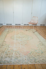 Distressed Oushak rug corner showing mostly even wear, visible foundation, and intact selvage.