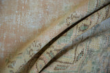 Distressed Oushak rug pile texture showing knot heads and soft pale rose, green shades.