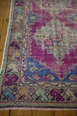 Vibrant purple, faded blue, and sand meandering vine border detail on a distressed Oushak runner.