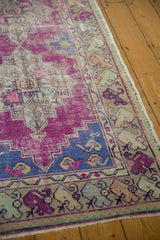 Vintage Oushak rug border with distressed floral cross sections and bright purple violet.