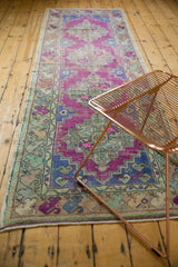 Secured end of distressed Oushak runner, showing fringe, floral, and vine borders.