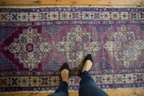 Distressed Oushak runner displaying violet, navy, sand medallions and fantastic abrashes.