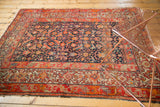 Antique Malayer hand-knotted rug showing navy Herati motif and multi-banded red, orange, beige borders.