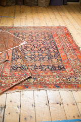 Worn antique Malayer rug, showing Herati motif field, geometric red border, and frayed side.