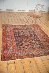 Antique Malayer rug corner detail, highlighting navy Herati field, red geometric borders, and tattered fringe.