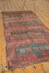 Vintage Kazak rug showing cochineal red field with elongated medallions, hook motifs, and bristly pile.