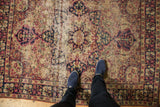 Worn antique Kerman rug's starburst medallion showing extensive threadbare areas.