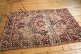 Lower corner of antique Kerman rug featuring a prominent threadbare stripe and navy cochineal floral border.