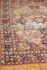 Antique Kerman rug exhibiting threadbare stripe, hard tatter, ivory, and red hues.