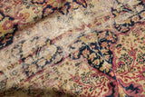 Detail of significant threadbare area and hard tatter on an antique Persian Kerman rug.