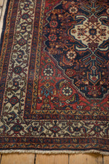 Bibikabad rug corner detail: fringed edge, ivory border, and red field with navy Herati motif.