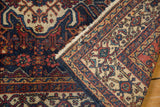 Hand-knotted vintage Bibikabad rug folded, revealing navy, red Herati motif pile and woven reverse.