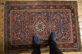 Detail of Dargezine rug corner, tattered fringe, and red, navy Herati motifs with light wear.